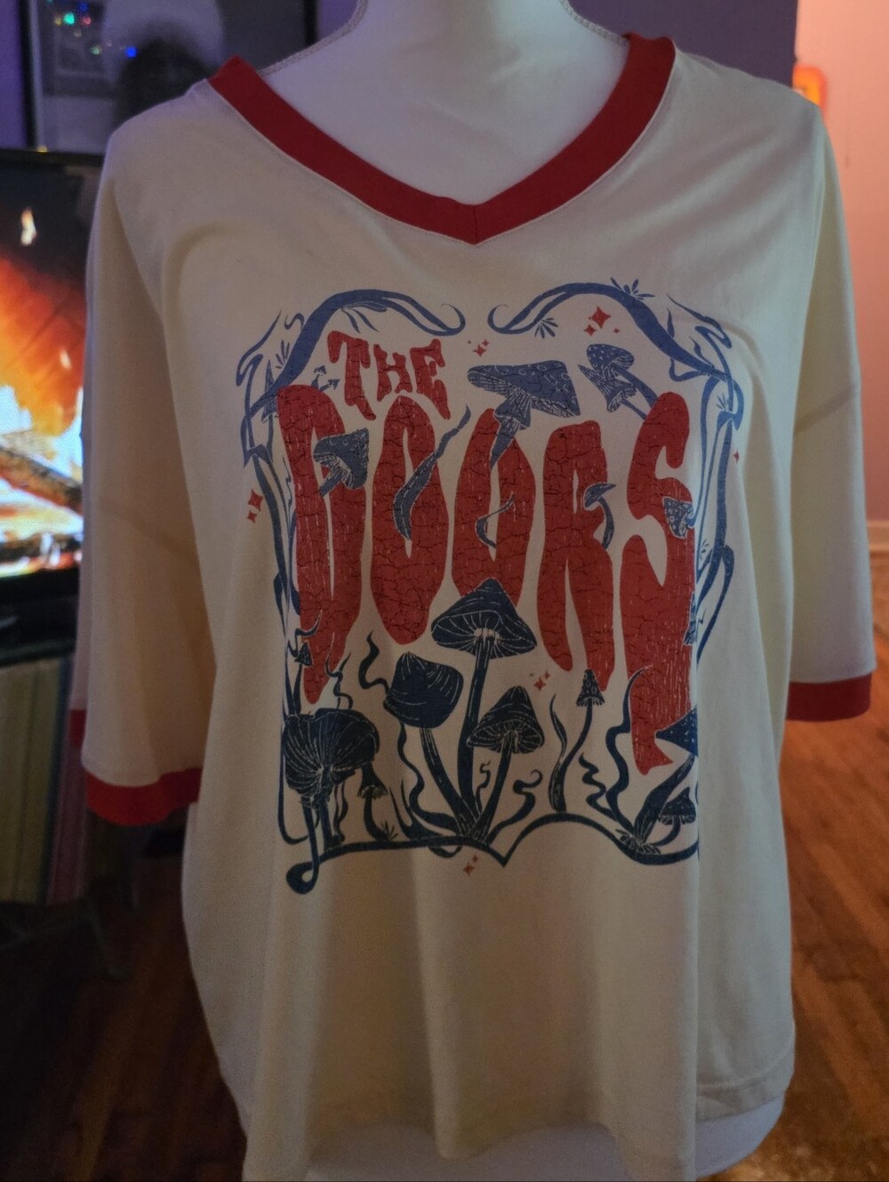 A cream cropped ringer t-shirt featuring a vibrant red and blue mushroom graphic